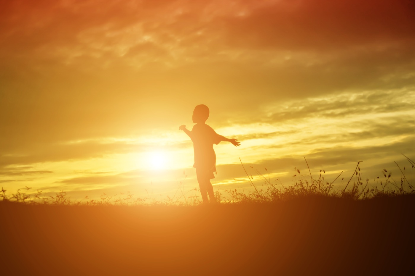 Kind im Sonnenuntergang, Arme ausgebreitet